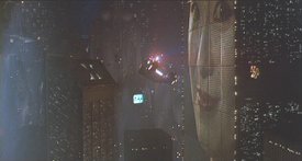 A police spinner flies alongside an advertising-laden skyscraper in LA.